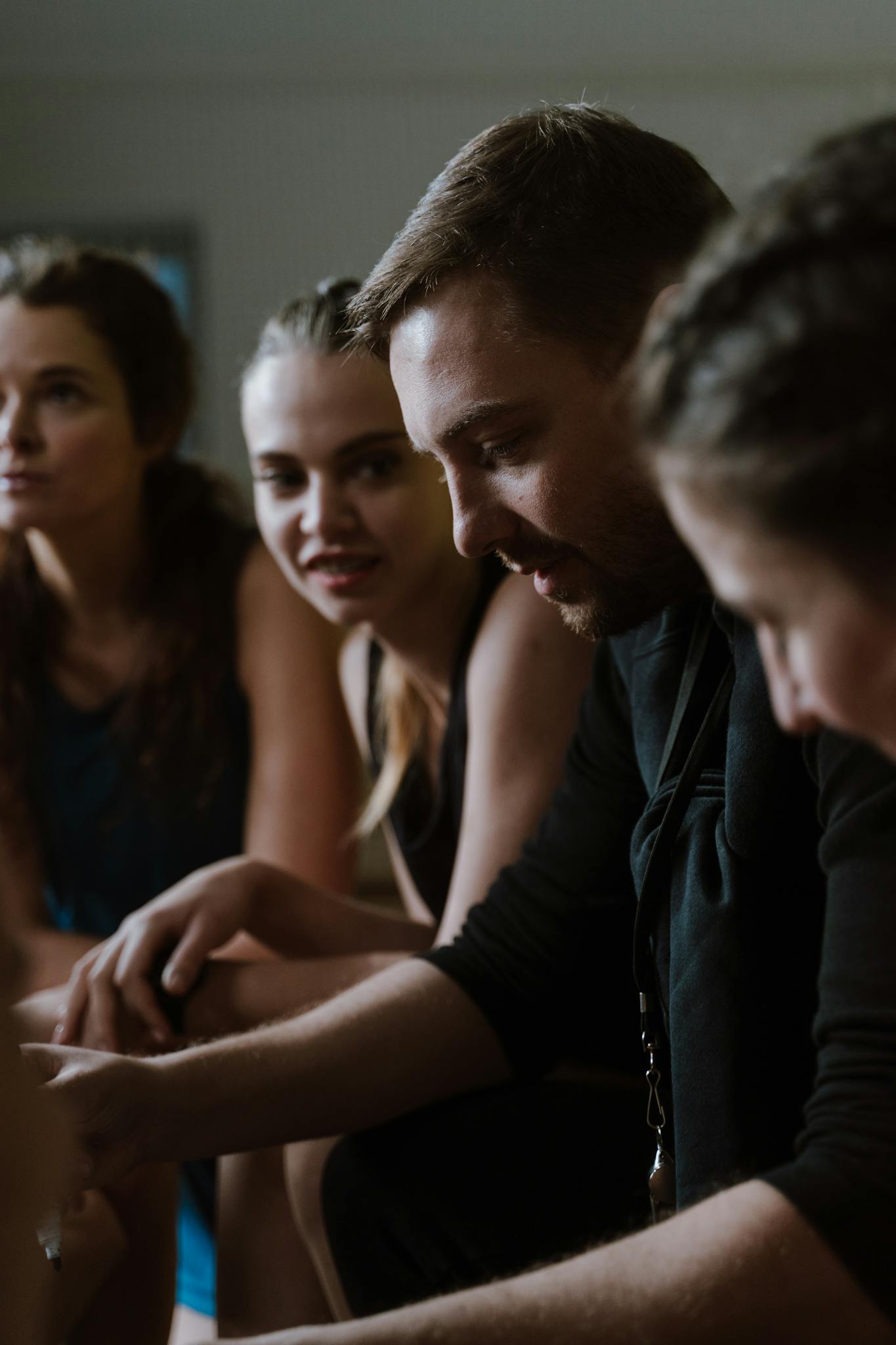 A sports team in a closely knit huddle with their coach indoors, showing teamwork and concentration.